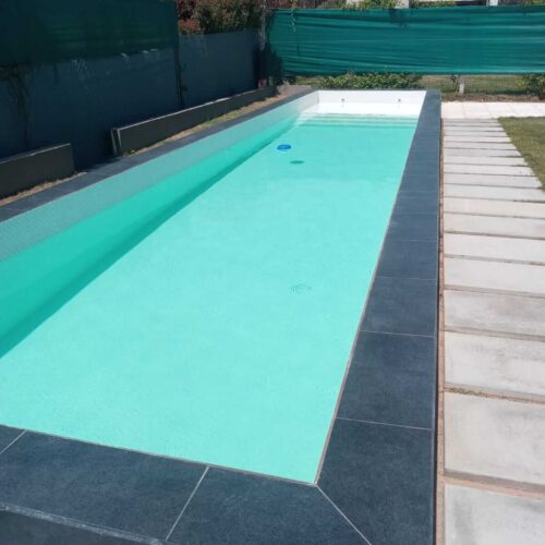 Piscina de material con camino de baldosas en su perímetro